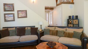 A spacious living room with a wooden floor, two sofas, a coffee table, and a staircase leading to another level.