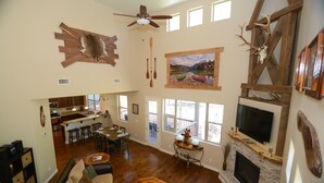 A spacious living area with a fireplace, wooden furniture, and a large TV mounted on the wall.