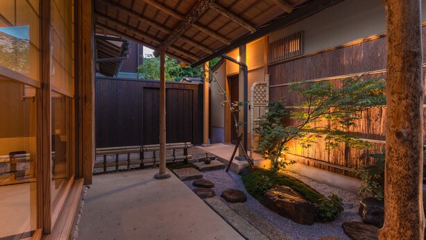 A traditional Japanese garden with a wooden deck, stone lanterns, and a small tree. - Kyoto SANARI Konoeden (Kyoto)