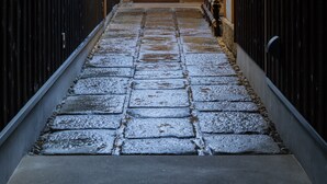 A narrow stone pathway leading to a traditional wooden door, flanked by dark wooden walls and a tiled roof. - Kyoto SANARI Konoeden (Kyoto)