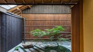 A wooden staircase leading to a covered outdoor area with a bamboo plant and stone steps. - Kyoto SANARI Konoeden (Kyoto)