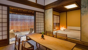 A traditional Japanese room with tatami flooring, a low wooden table, and a futon bed. - Kyoto SANARI Konoeden (Kyoto)