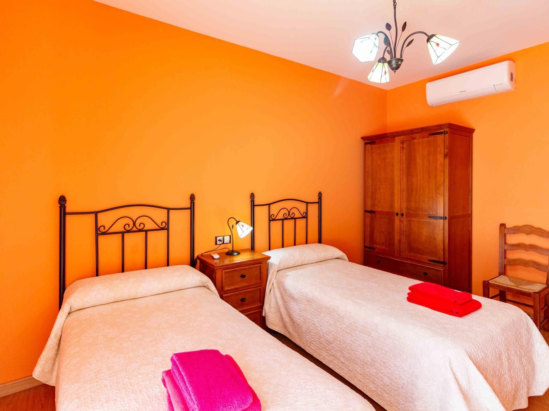 Ein Zimmer mit zwei Betten, einem Holzschrank, einem Nachttisch mit Lampe und einem Stuhl.