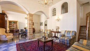 A spacious living room with a high ceiling, a stone pillar, and a patterned rug.