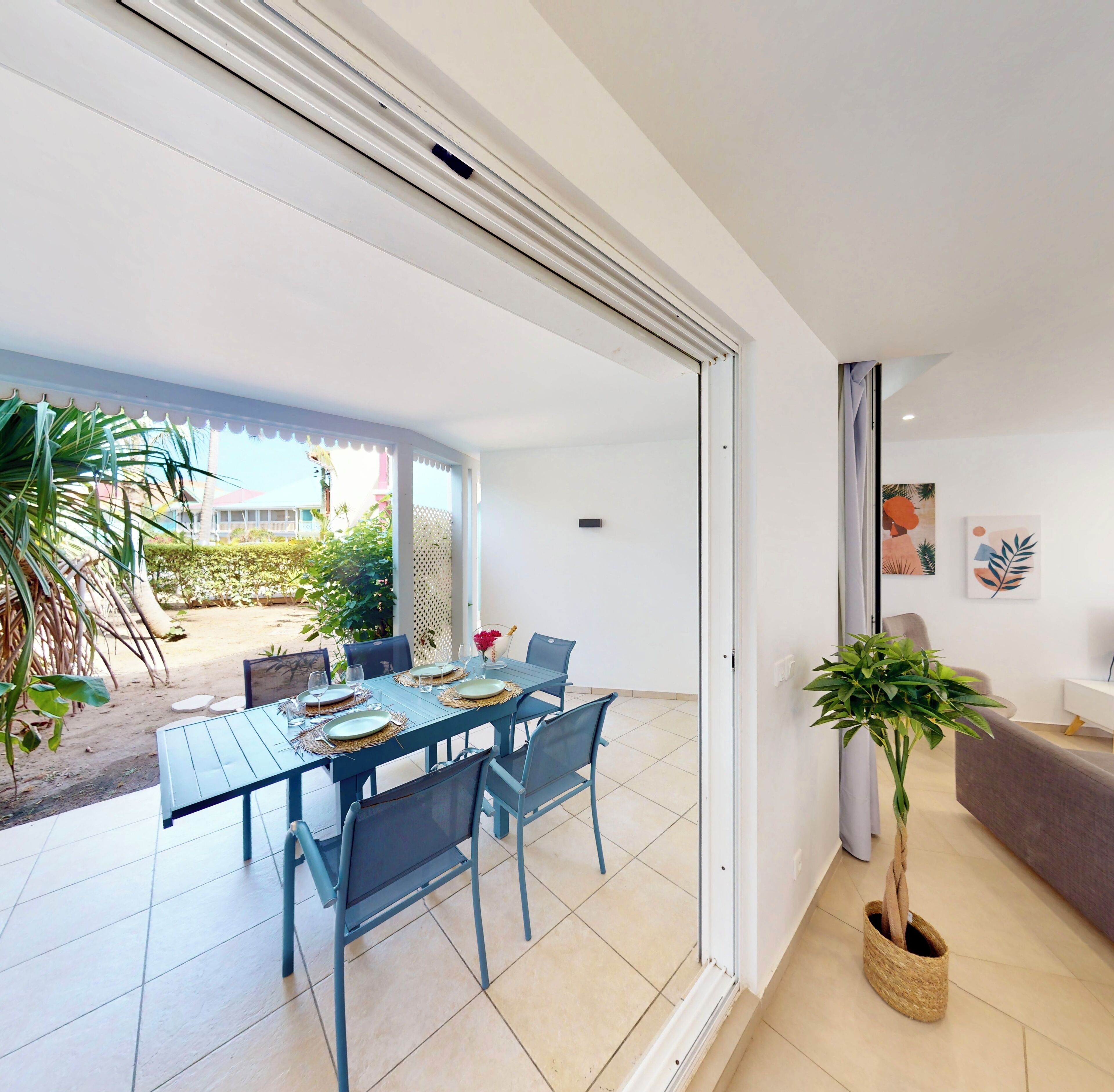 A dining area with a table set for four, a sofa, and a potted plant.