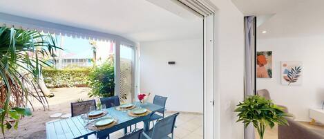 A dining area with a table set for four, a sofa, and a potted plant.