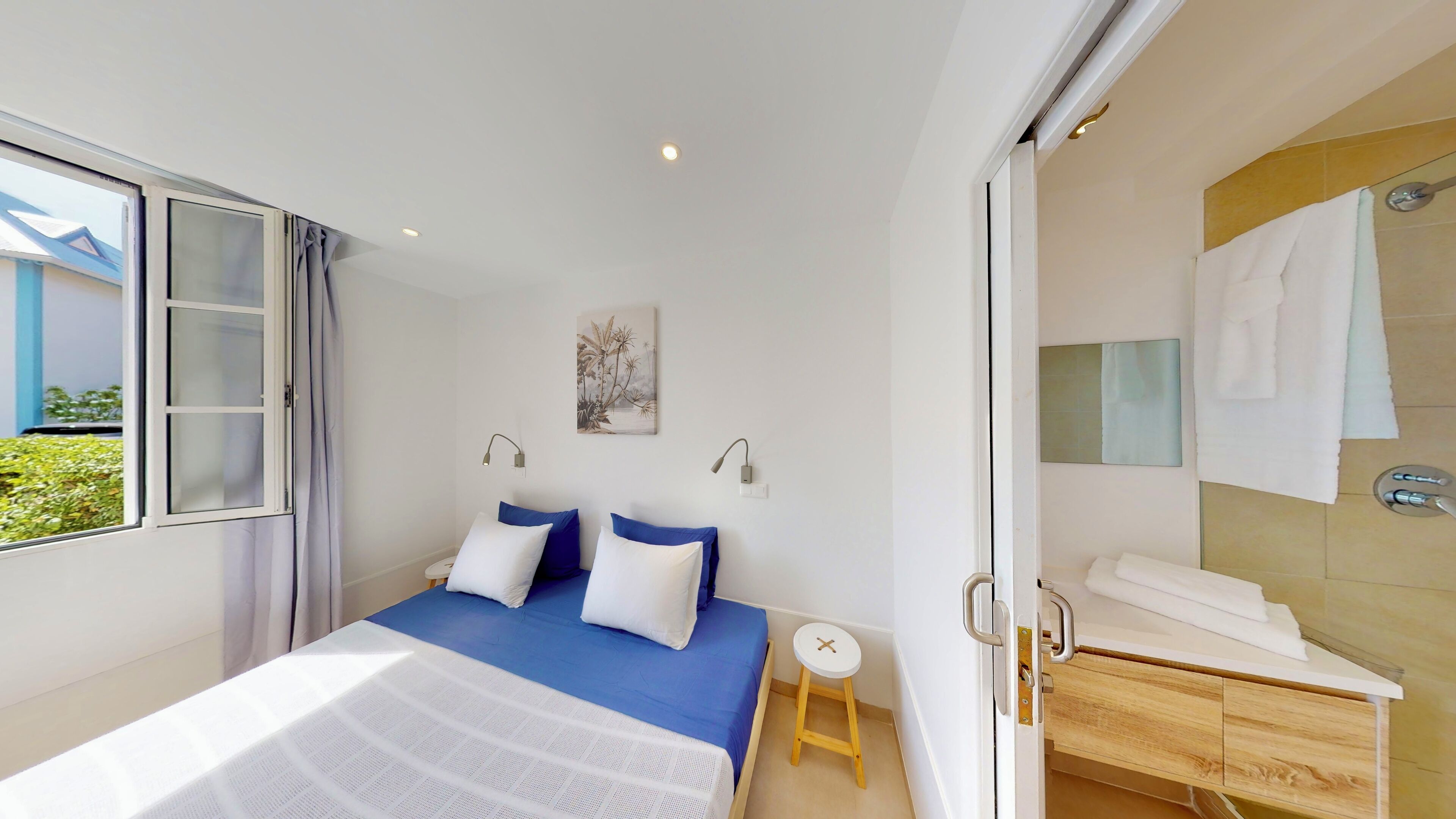 A bedroom with a bed, bedside table, and a view of the outside.