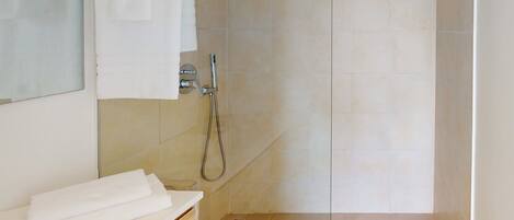 Un baño moderno con ducha, tocador de madera y espejo.