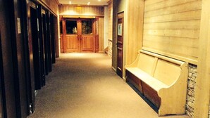A hotel corridor with wooden doors, a bench, and a stone wall. - Arc 2000, studio direct access to  tracks, South balcony (Bourg-Saint-Maurice)