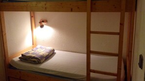 A bunk bed with a wooden ladder, a single bed with a quilt, and a wall-mounted light fixture. - Arc 2000, studio direct access to  tracks, South balcony (Bourg-Saint-Maurice)