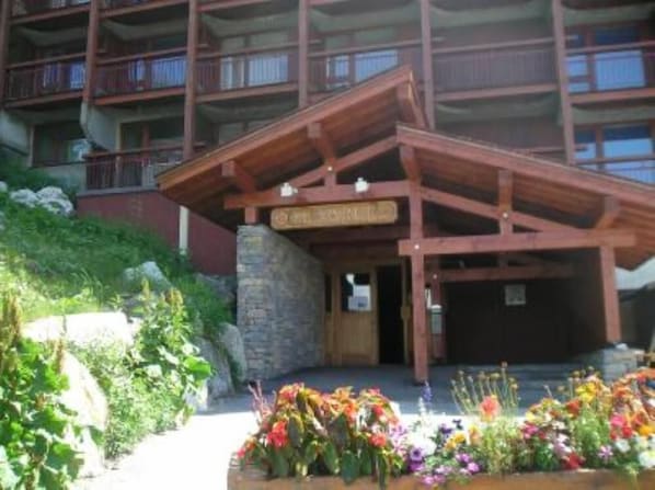 A multi-story building with a wooden entrance and a sign indicating it is a hotel.