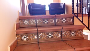 Una escalera con elaborados diseños de azulejos y dos sillas negras al final.