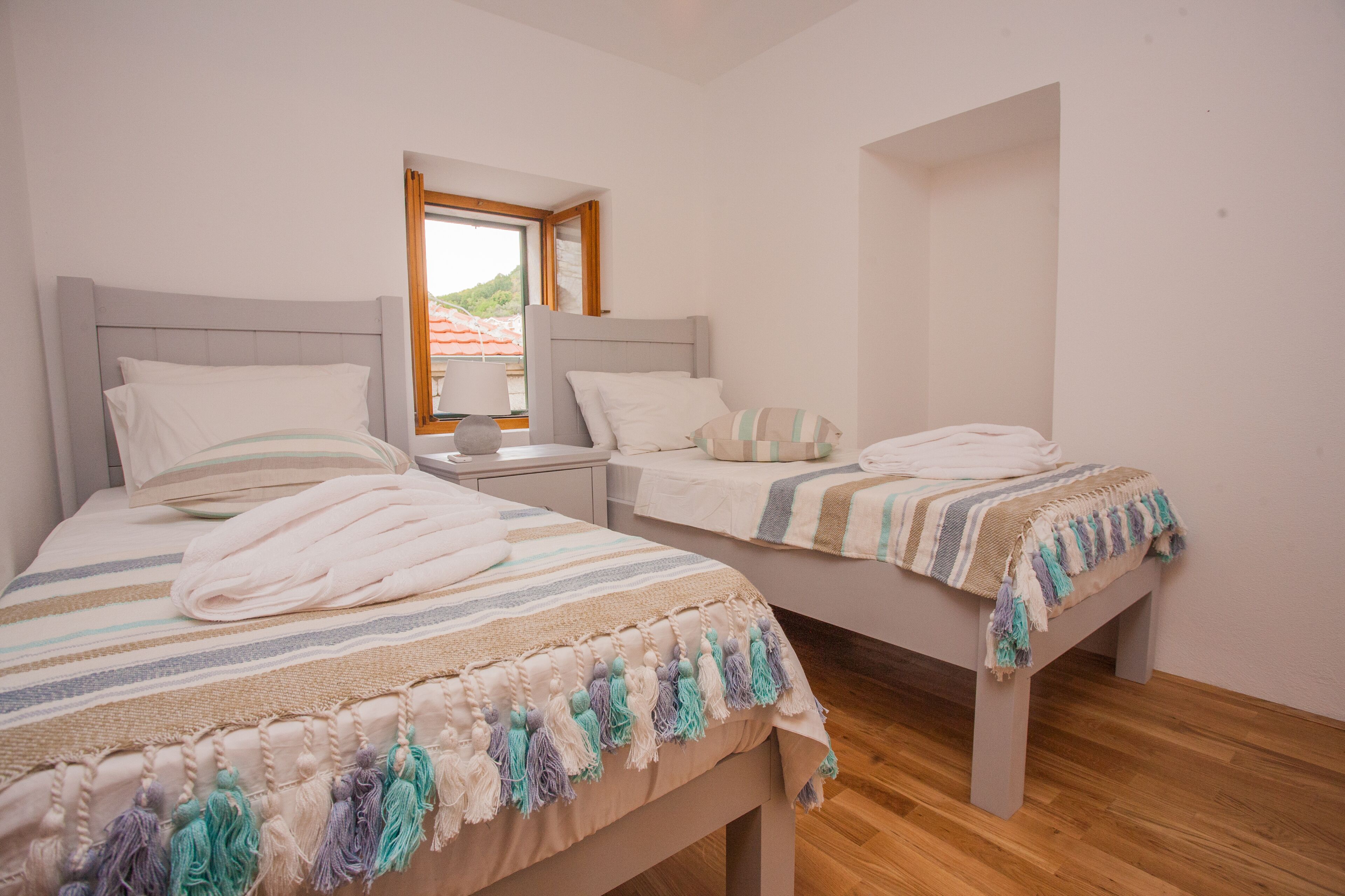 Quarto de hotel com duas camas, cada uma com um cobertor listrado e uma almofada.