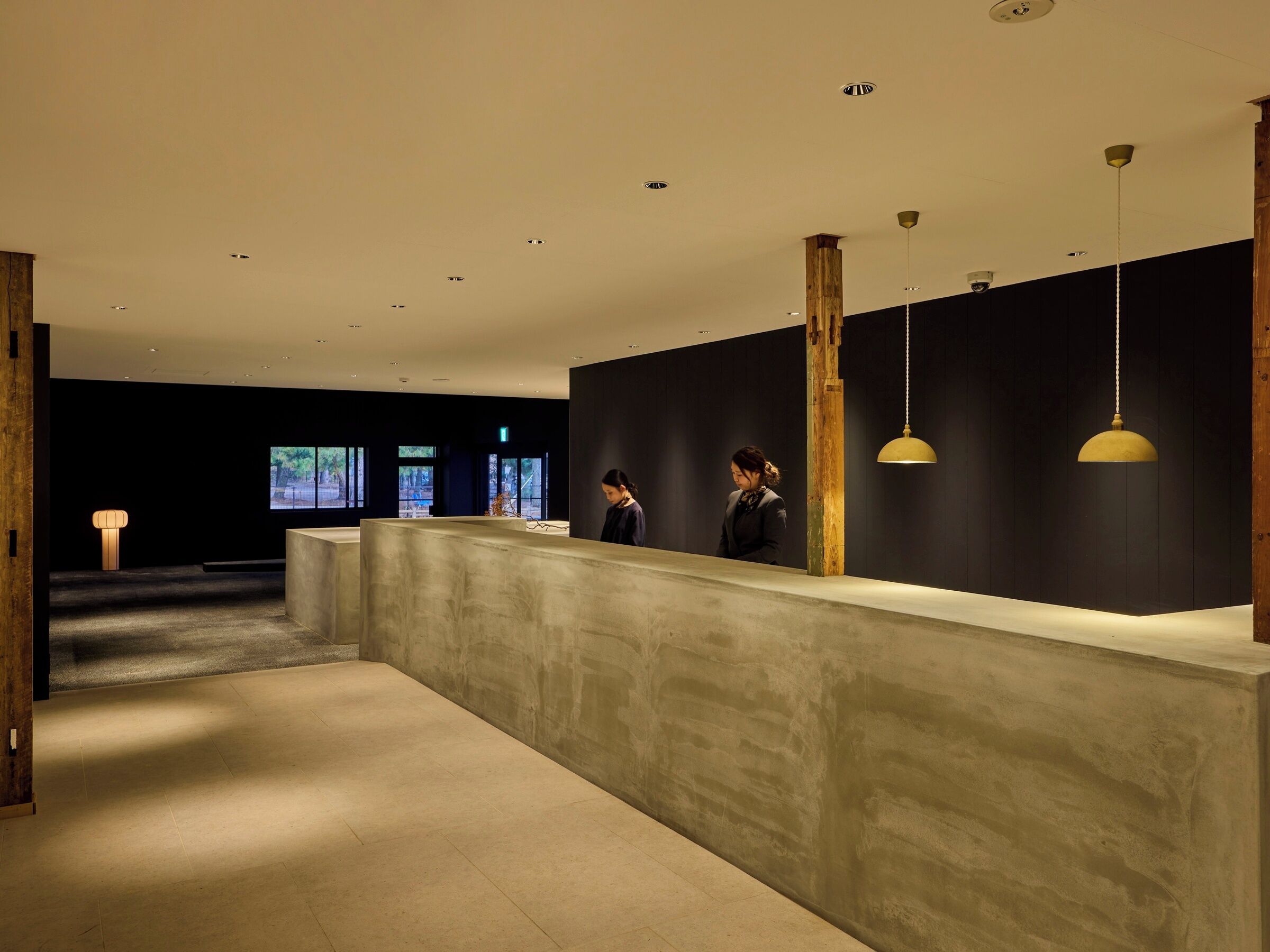 A reception area with a reception desk, wooden columns, and pendant lighting.