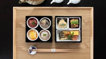 A wooden tray with various Japanese dishes, chopsticks, and two teapots.