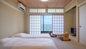 A hotel room with a large bed, a small table, a chair, and a TV. - ONCRI-KARATSU (Karatsu)