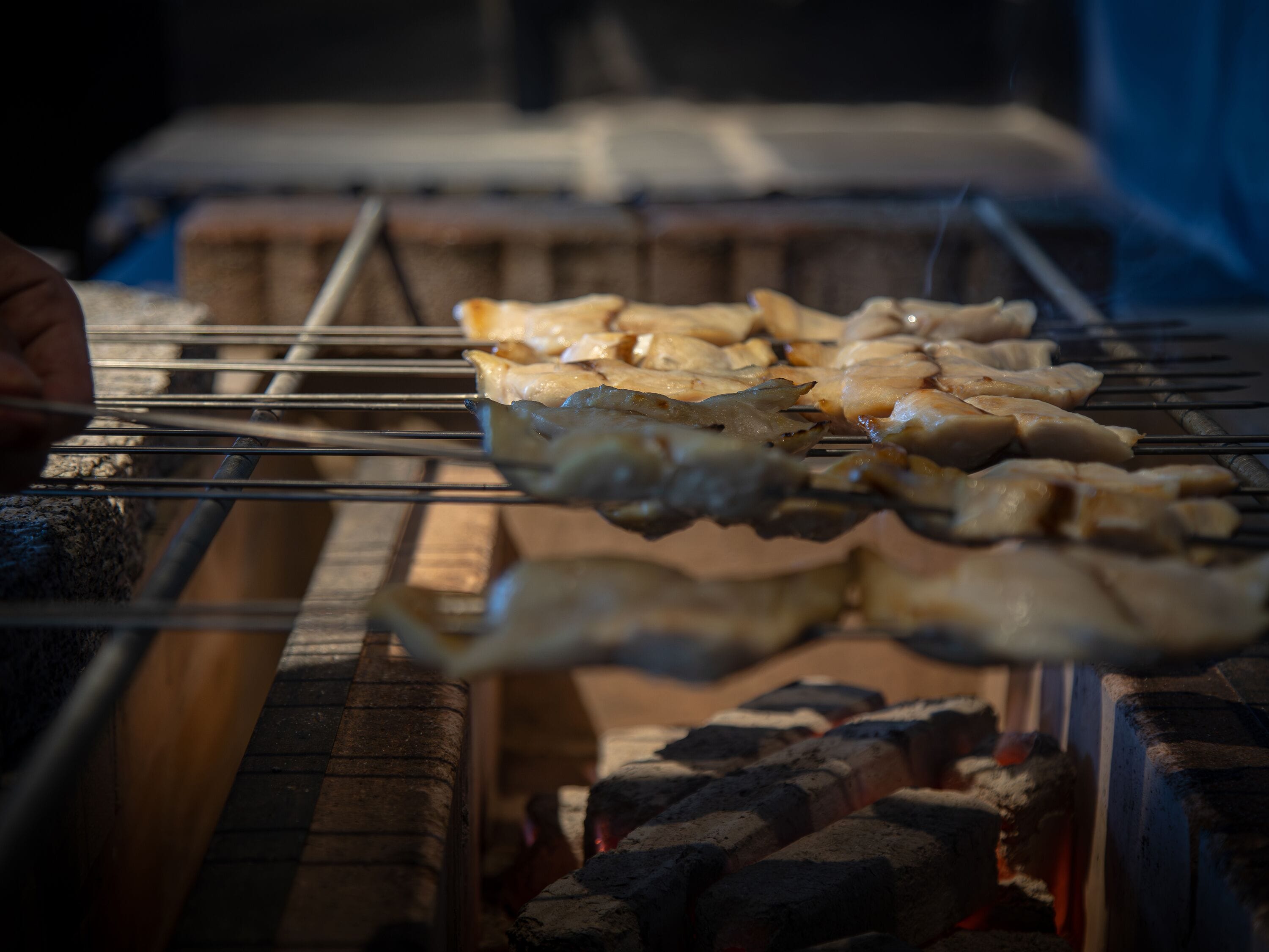 Skewers of food being grilled over charcoal.