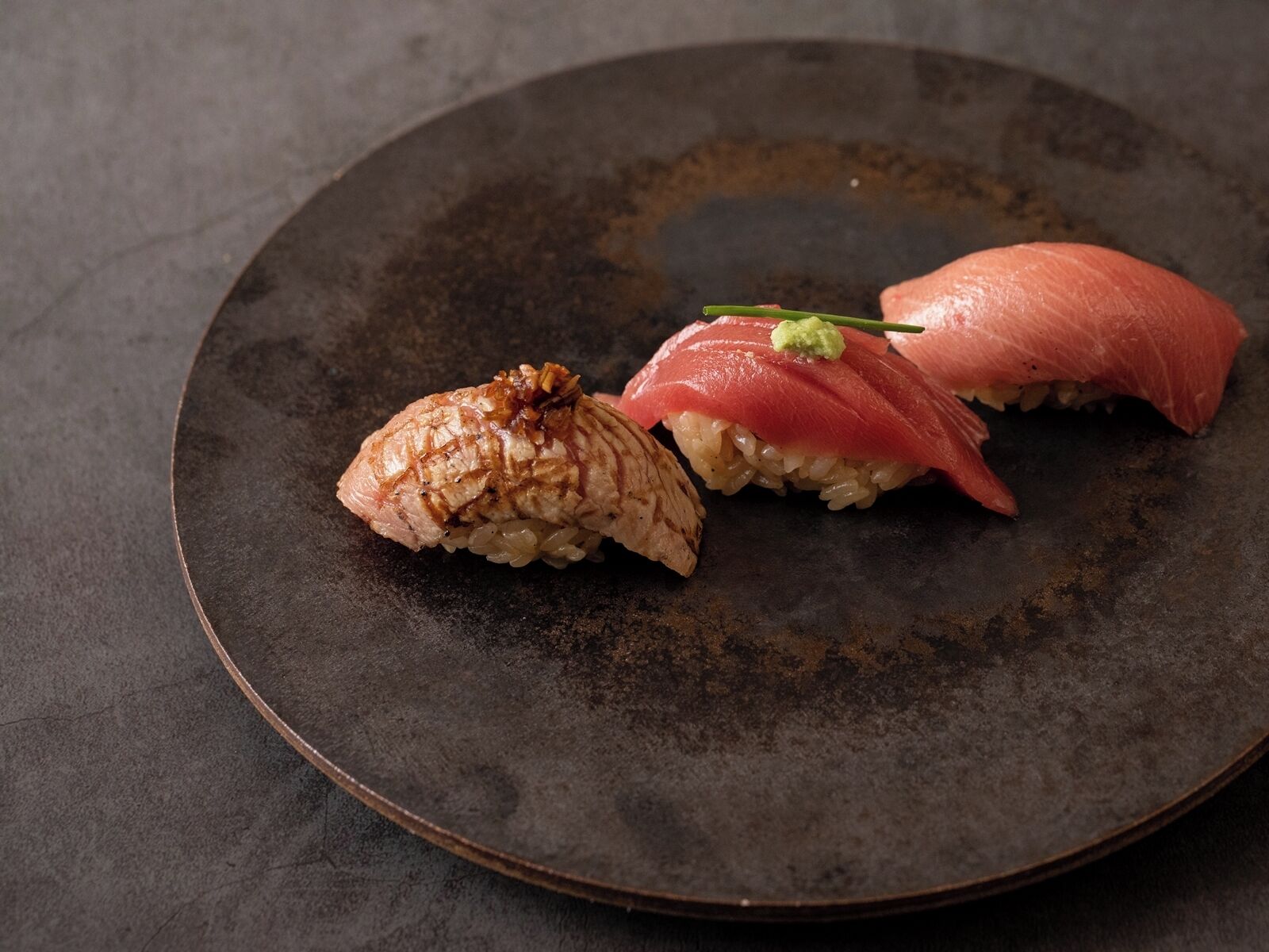 Ein Teller mit zwei Sushi-Stücken, eines mit Belag und das andere mit Garnitur.