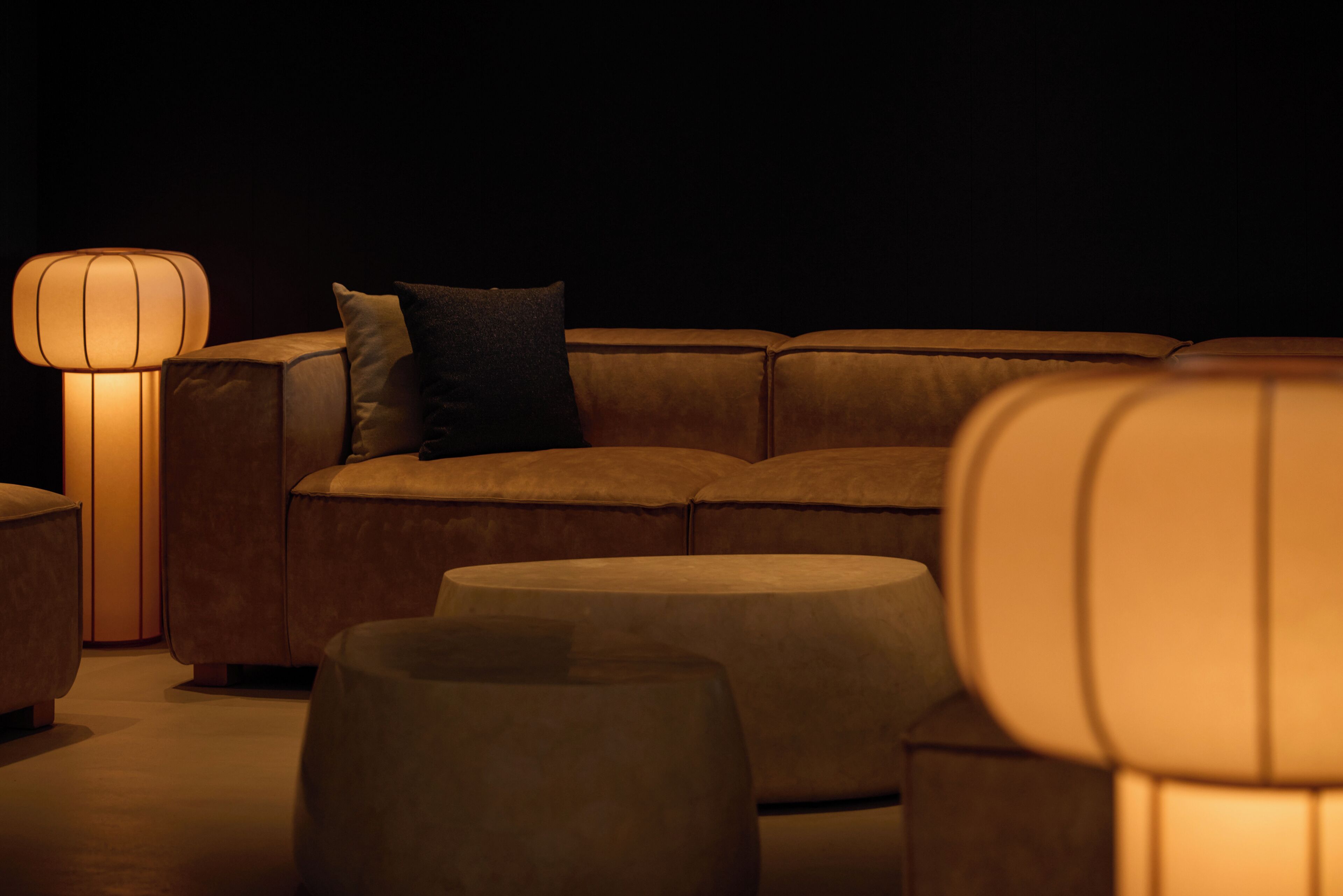 En moderne stue med sofa, skammel og gulvlampe.