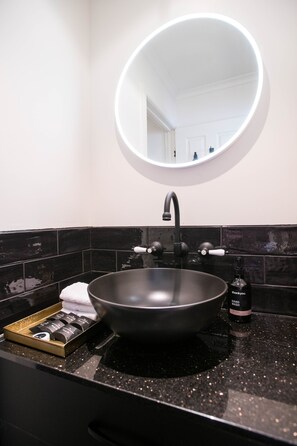 A modern bathroom with a black sink, a round mirror, and a hand wash bottle. - Battery Point Boutique Accommodation (Battery Point)