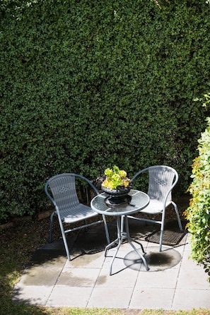 A patio with two metal chairs and a round table, surrounded by a neatly trimmed hedge. - Battery Point Boutique Accommodation (Battery Point)