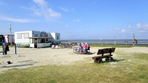 A beachside cafe with outdoor seating, a playground, and a bench. - Spacious vacation residence for 6 pers. with pool and garden. Sauna - shared use (Stadland-Reitland)