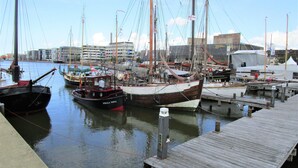 A marina with several boats docked, wooden piers, and a cityscape in the background. - Spacious vacation residence for 6 pers. with pool and garden. Sauna - shared use (Stadland-Reitland)