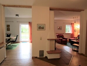 Un vaste espace de vie comprenant une table à manger, des chaises, une cheminée et un coin salon avec un canapé et des fauteuils.