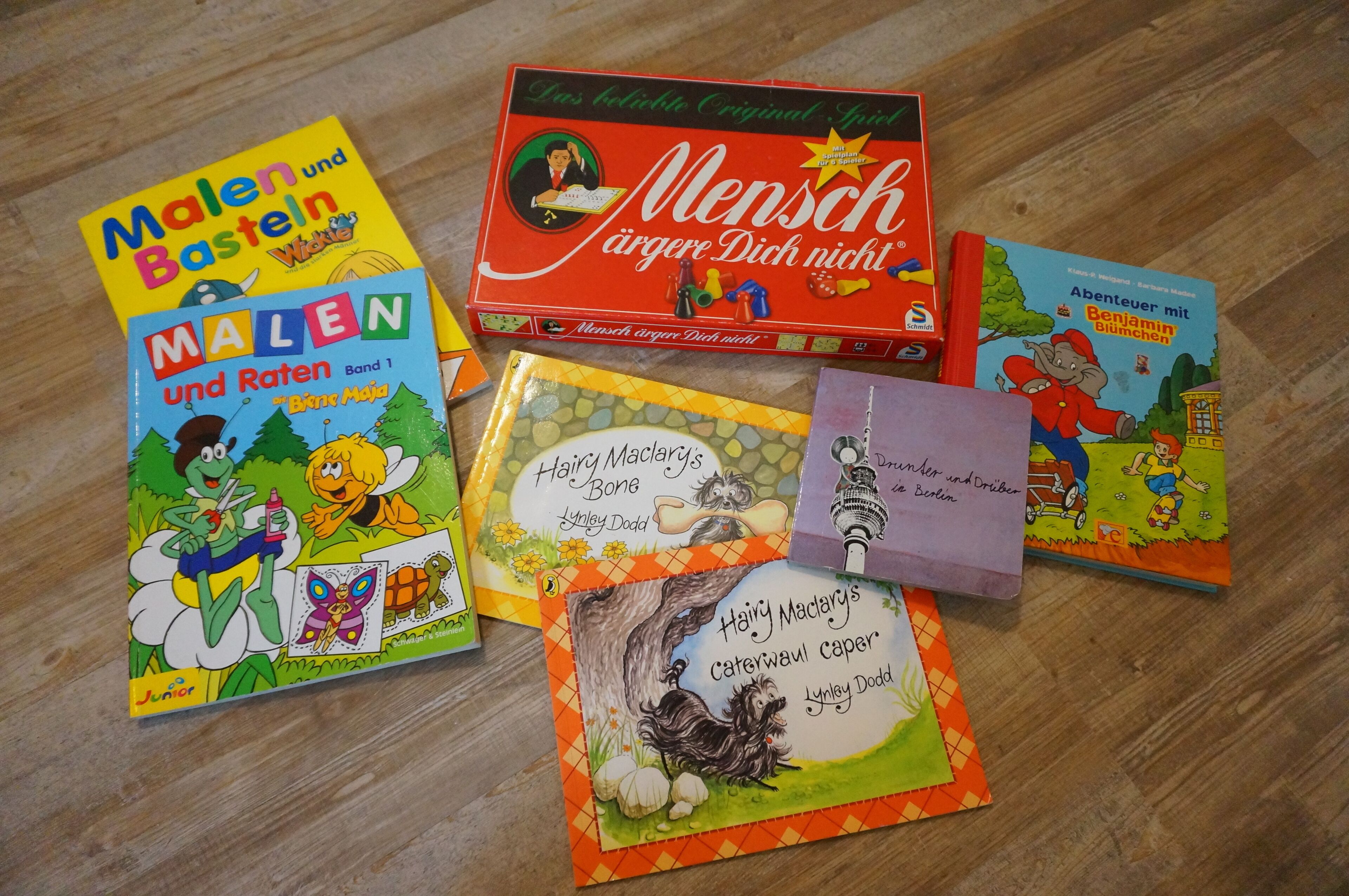 A collection of children's books on a wooden floor.
