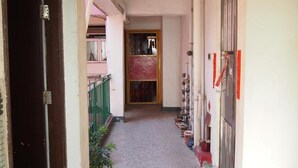 A corridor with a tiled floor, a door on the left, and a red pipe overhead. - Ukkei Inn (Kowloon)