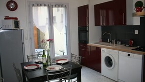 Cocina compacta con lavadora, microondas y comedor con mesa dispuesta para dos.