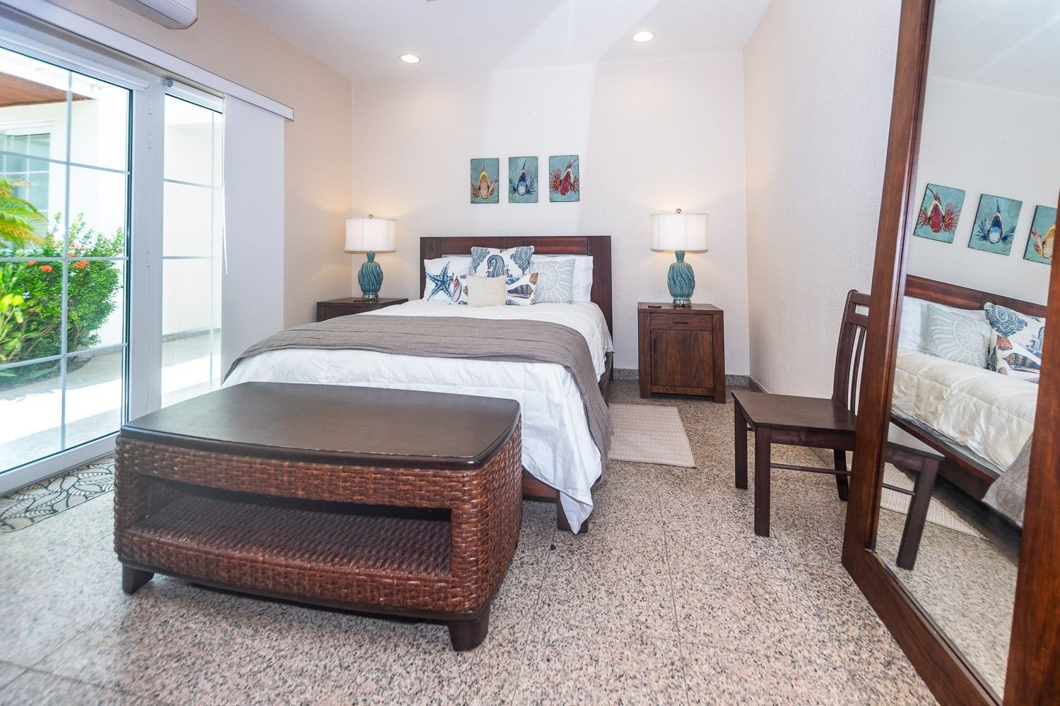 A bedroom with a bed, bedside tables, a chair, a large mirror, and artwork on the walls.