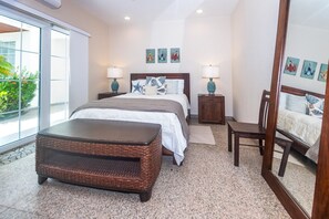 A bedroom with a bed, bedside tables, a chair, a large mirror, and artwork on the walls. - Lawson Rock - Angelfish 100 (Roatan)
