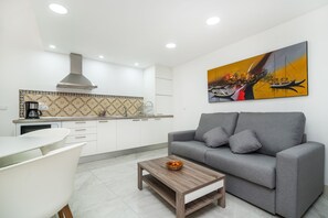 A modern kitchen with white cabinets, a gray sofa, and a coffee table.