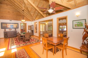 A spacious dining area with a wooden table and chairs, a ceiling fan, and a large mirror reflecting the room. - Casa de Admirada (Roatan)