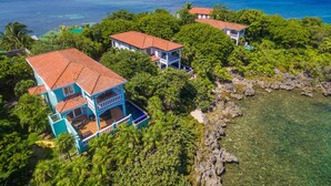 A coastal property with multiple buildings surrounded by lush greenery and clear blue waters. - Coral Vista #3 (Roatan)