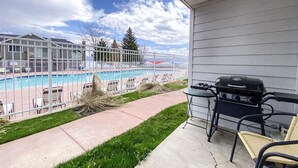 A balcony with a view of a swimming pool, a grill, and outdoor furniture. - Inn Building Condo#113 - Ground Level, Pool Side (Garden City)