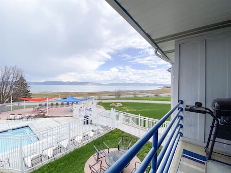 A balcony with a pool, outdoor seating, and a view of a park and mountains.