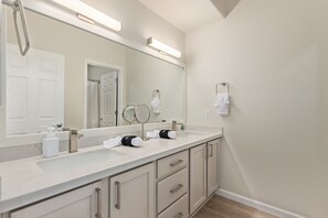 A bathroom with a large mirror, two sinks, and a towel rack.