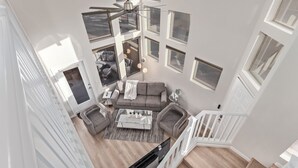 Ein großzügiger Wohnbereich mit grauem Sofa, einem Couchtisch und einem Deckenventilator.