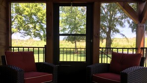 A porch with wicker chairs and a view of a green landscape.