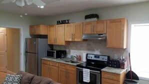 A kitchen with wooden cabinets, a microwave, a stove, and a ceiling fan. - 1 BR located 5 minutes away from St Joseph & Hackensack Hospital. 15 min to NYC  (Paterson)