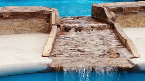 Une piscine agrémentée d’une cascade en pierre.