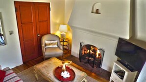 Un salón acogedor con chimenea, televisor y un sillón cómodo.