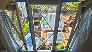 A view through a window with a lattice fence, outdoor furniture, and potted plants.