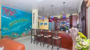 Une cuisine avec un coin bar, une fresque murale et une décoration en forme de tronc d’arbre en bois.