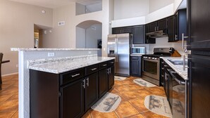 A modern kitchen with granite countertops, stainless steel appliances, and dark cabinetry.