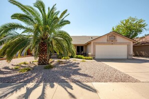 A residential house with a single garage, a palm tree in the driveway, and a clear sky. - Westgate Vacation Rental/Walk to State Farm Stadium/Relax in the Spa! (glendale)