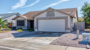 A single-story house with a garage, a small porch, and a gravel driveway.
