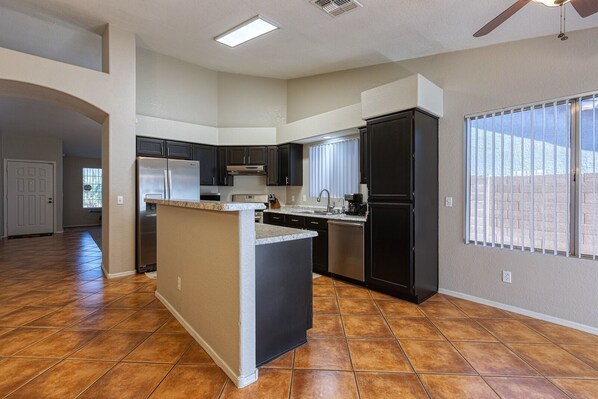 A spacious kitchen with dark cabinets, a granite countertop island, and a large window. - Westgate Vacation Rental/Walk to State Farm Stadium/Relax in the Spa! (glendale)